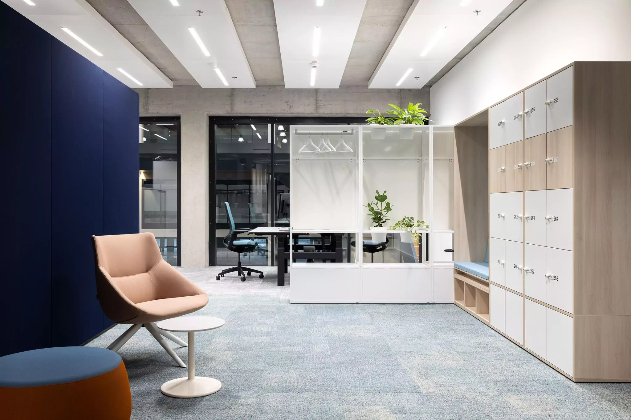 Blick in eine moderne Arbeitswelt mit Sessel und Beistelltisch sowie Schreibtisch im Hintergrund