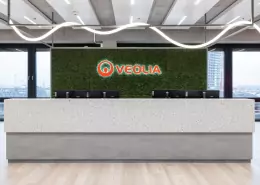 Empfangstheke, dahinter ein Veolia Schriftzug in rot auf grünem Mooshintegrund