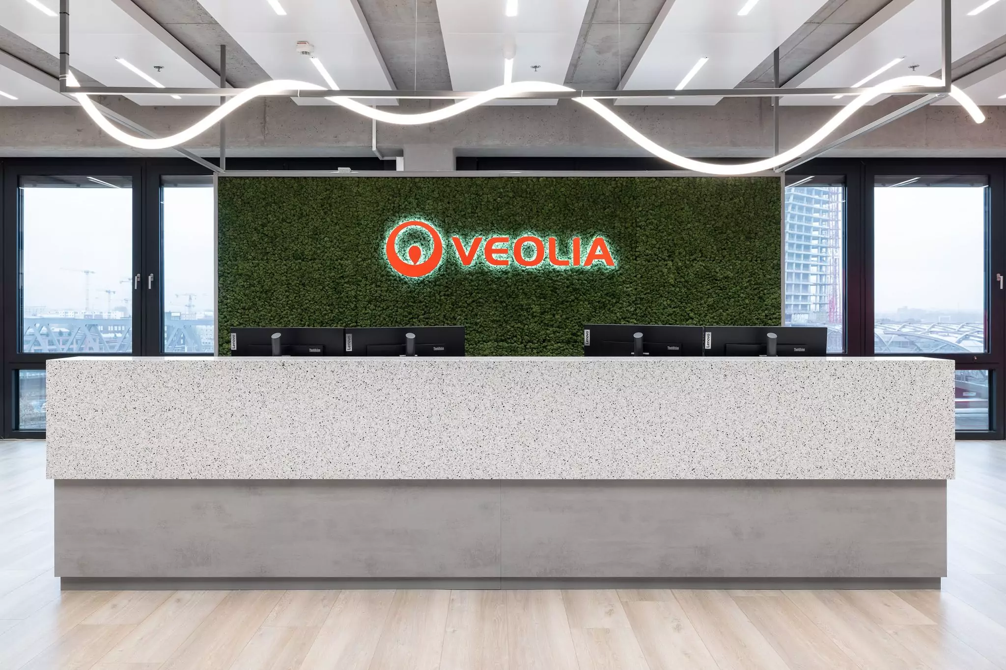 Empfangstheke, dahinter ein Veolia Schriftzug in rot auf grünem Mooshintegrund